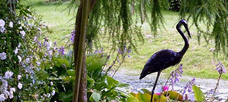 A well-stocked garden bed with sculpture forms an interesting focal point in the garden.