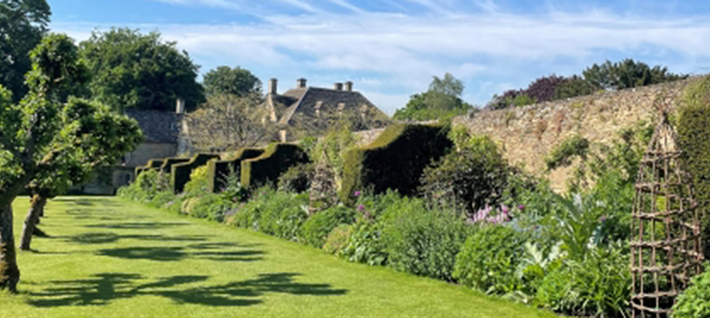 A well-stocked stone walled bed, along with fruit trees in the lawn, lead to the house.