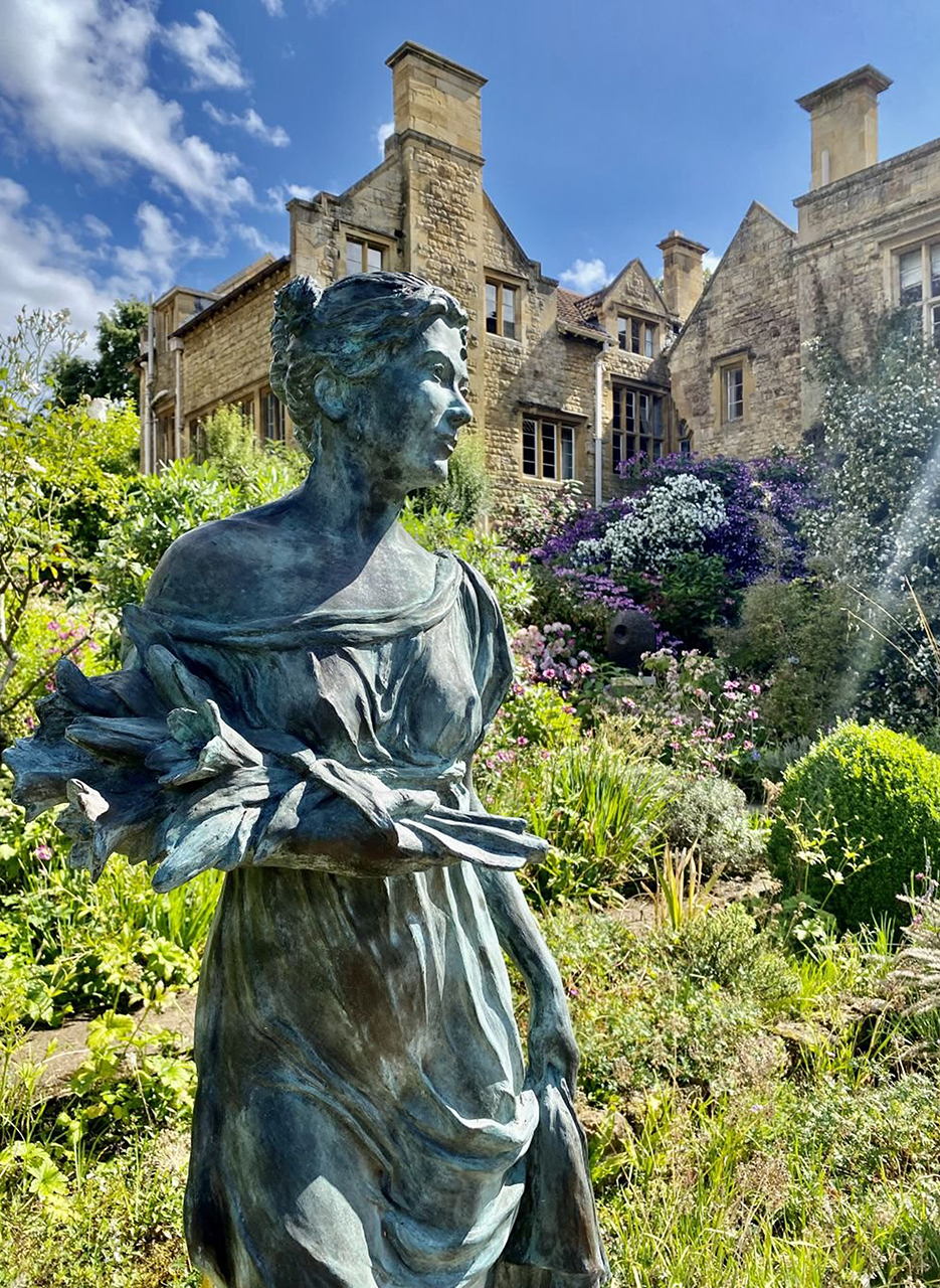 A beautiful statue in the foreground with the gardens and Kiftsgate Court in the background.